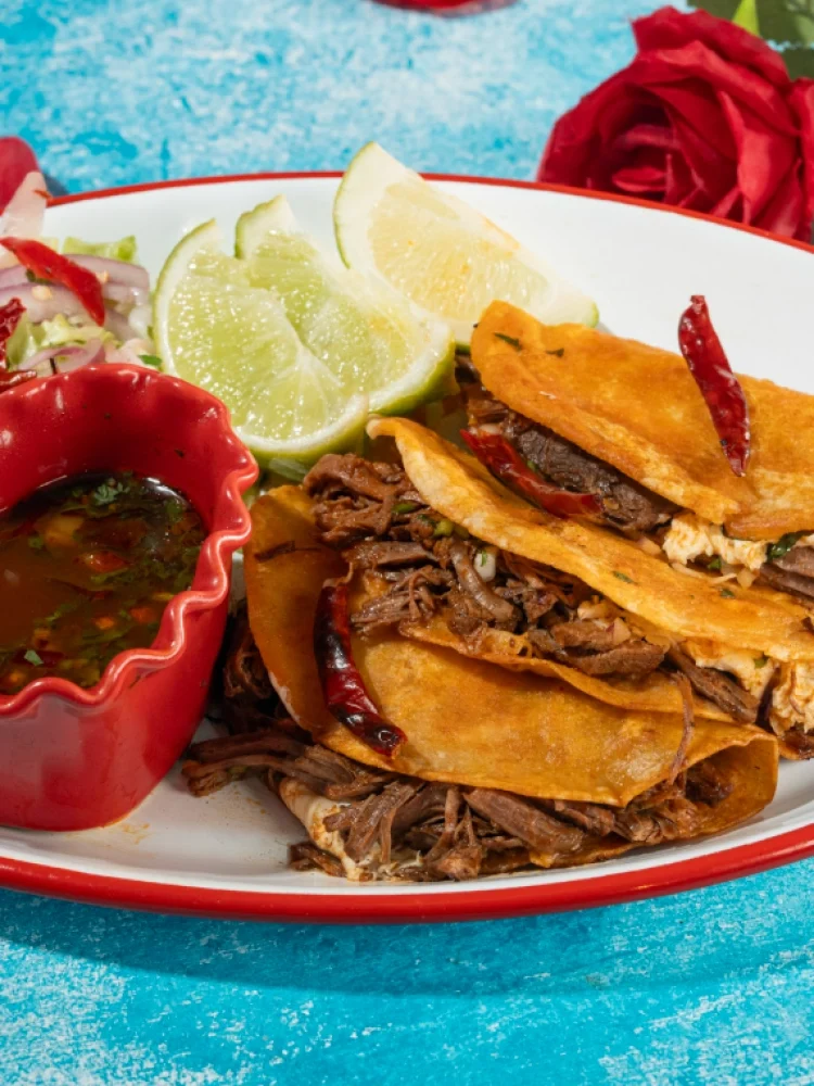 A plate of birria tacos with shredded beef, served with consommé and lime at the Despecho Room restaurant in Garfield, NJ.