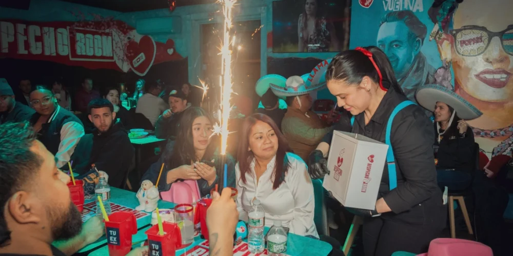Customers celebrating a special occasion with sparklers while a waitress presents a celebration package at Despecho Room in Garfield, NJ.